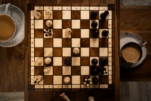 Partie de jeu d’échecs en bois sur échiquier pliant avec pièces sculptées – ambiance conviviale avec café