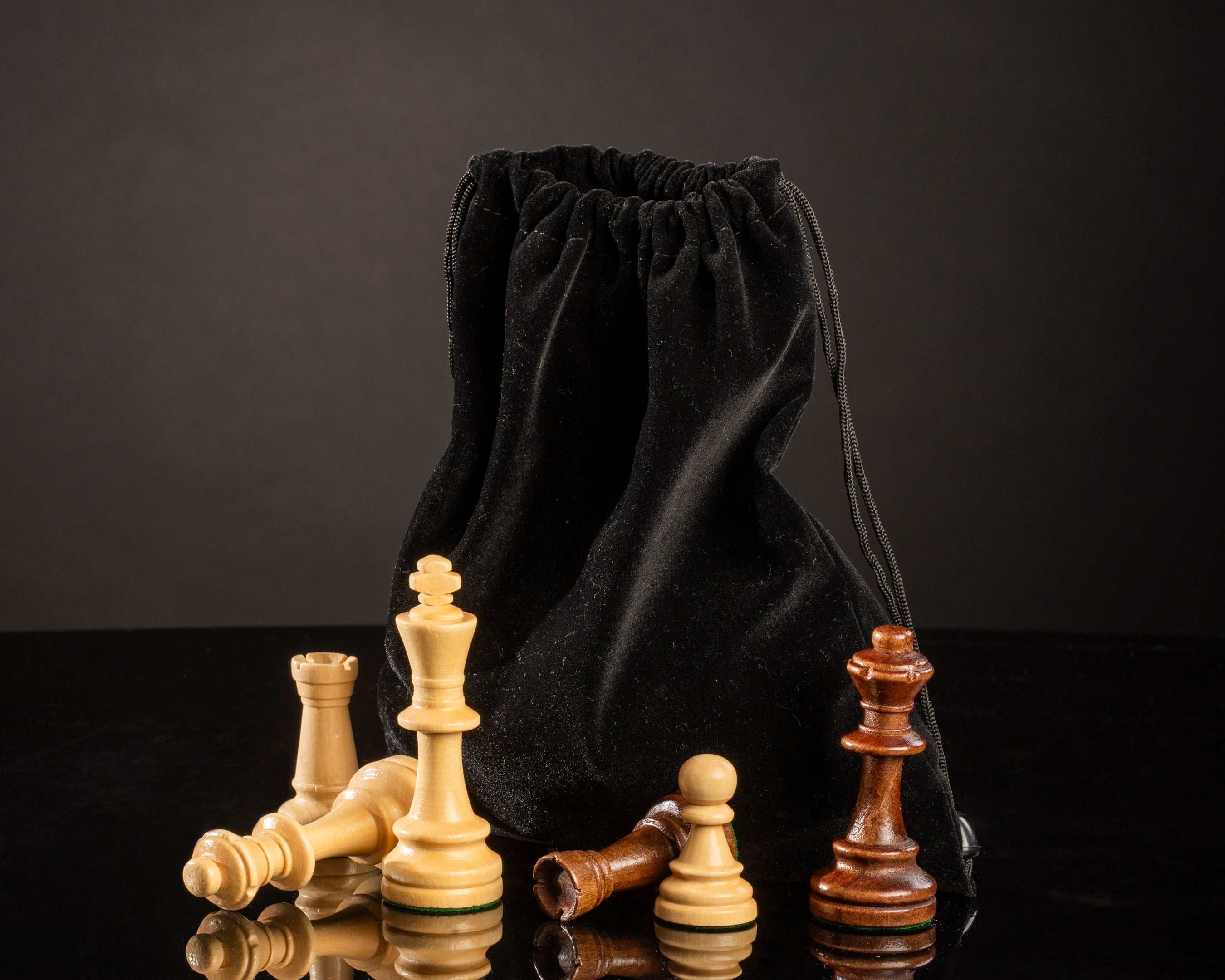 Sac de rangement en velours noir pour pièces d’échecs avec rois, tours et pions en bois sur fond noir