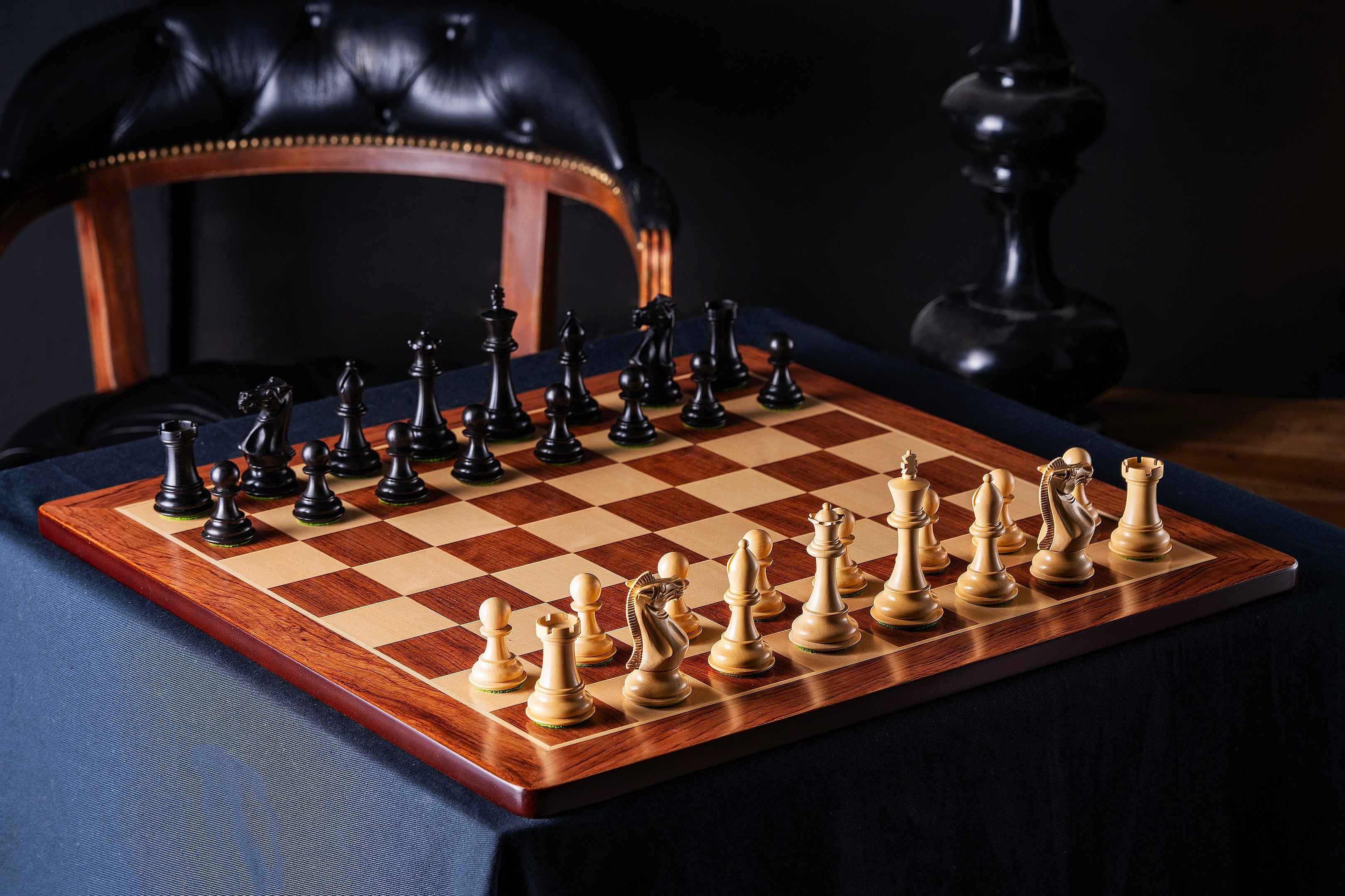 Échiquier en bois aux bords arrondis avec pièces noires et blanches sur une table élégante, idéal pour les passionnés d'échecs